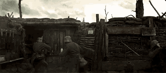 a group of soldiers are standing in a trench looking out of a doorway .
