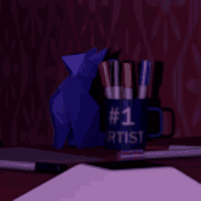 a blue mug that says # 1 artist sits on a desk