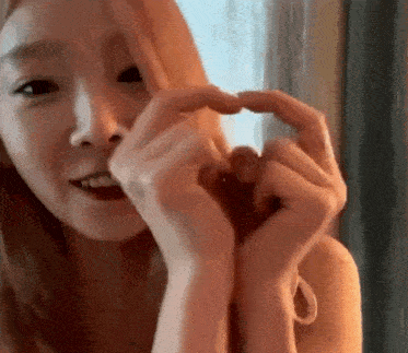 a young woman is making a heart shape with her hands .