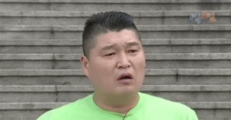 a man wearing a green shirt is standing in front of a staircase .