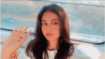 a woman is waving her hand while taking a selfie on a train
