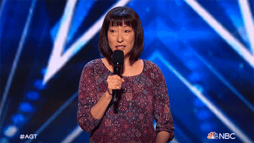 a woman is holding a microphone on a stage with a nbc logo in the corner