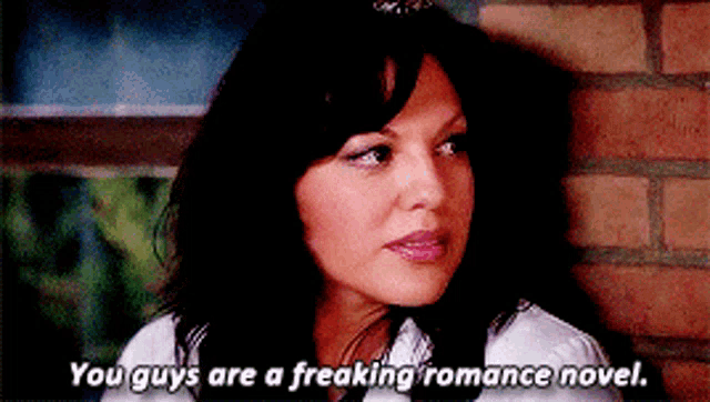 a woman is leaning against a brick wall and says you guys are a freaking romance novel