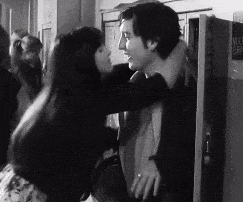 a black and white photo of a woman hugging a man in front of a vending machine that says ' curry ' on it