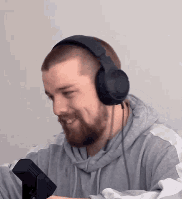 a man with a beard wearing headphones and a grey sweatshirt