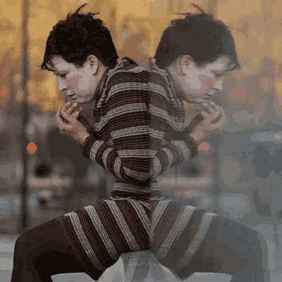 a woman in a striped sweater is sitting on a stool
