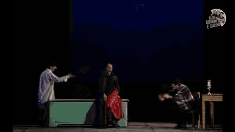 a man wearing a hat and a blanket is standing on a stage with candles in the background .