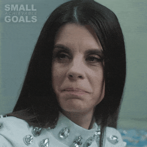 a woman 's face is shown in front of a small achievable goals poster