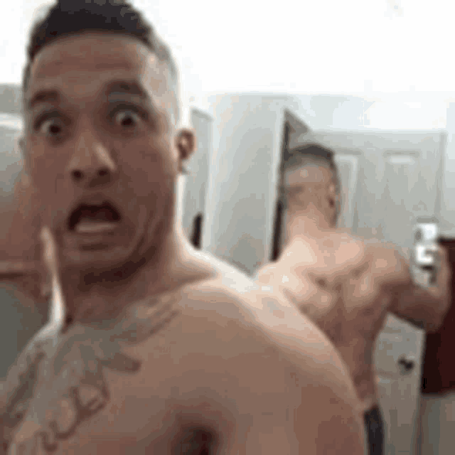 a shirtless man is taking a picture of himself in the mirror .