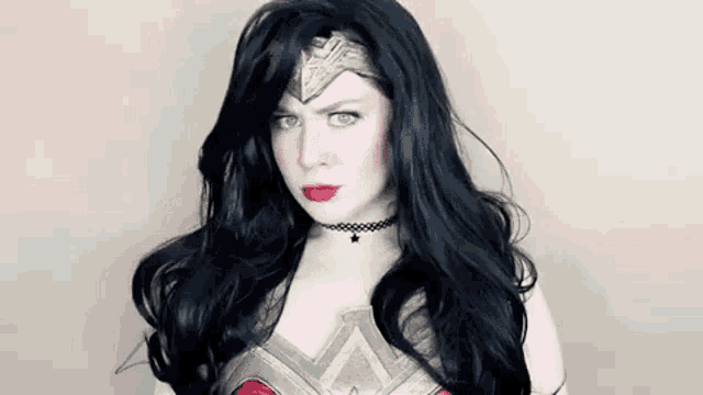 a woman with long black hair is wearing a wonder woman costume and making a funny face .