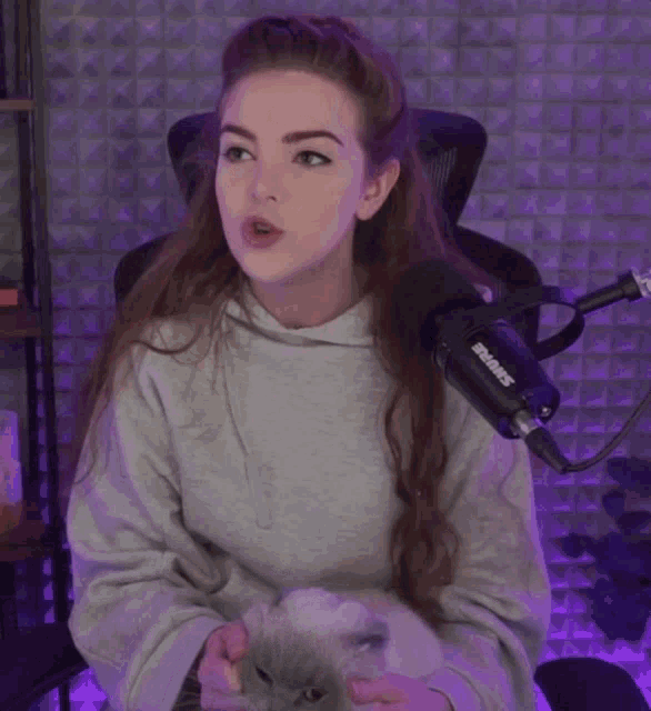 a woman holding a cat in front of a microphone that says shure