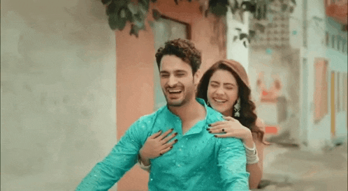 a man and a woman are laughing and hugging each other while riding a bike .