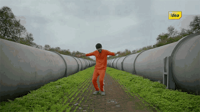 a man in orange pants is dancing in a field with a yellow idea logo in the background