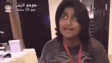 a woman is making a funny face in a room while wearing a lanyard around her neck .