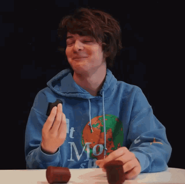 a man wearing a blue hoodie that says ' t mo ' on the front