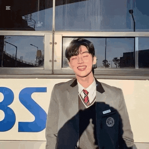 a man in a suit and tie is standing in front of a bus .