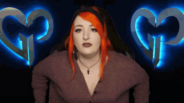 a woman with red hair is standing in front of a heart with the letter g on it