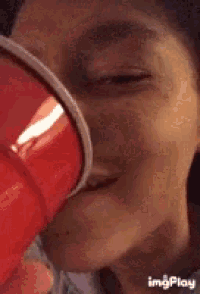 a woman is drinking from a red cup .