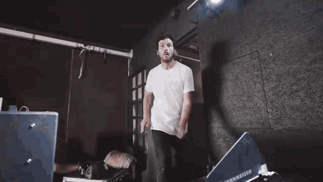 a man in a white t-shirt stands in front of a sennheiser speaker