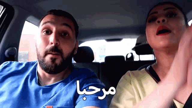 a man and a woman are in a car with arabic writing on the back