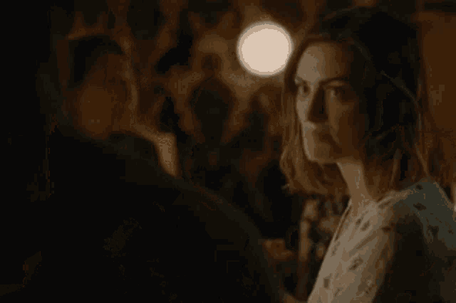 a woman is smiling at a man in a dark room while looking at him .
