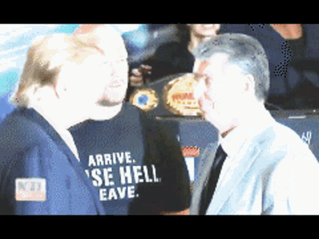a man wearing a shirt that says arrive se hell eave talks to another man