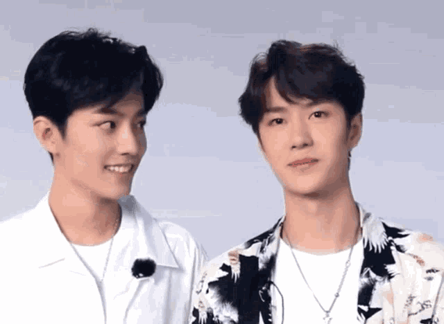 two young men are standing next to each other and smiling at each other