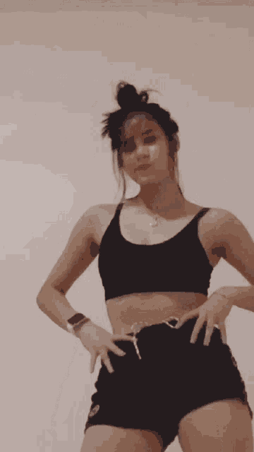 a woman in a black crop top and shorts is dancing