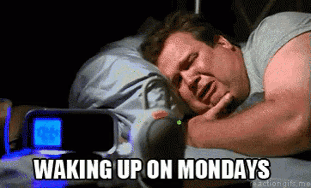 a man is laying in bed with the words waking up on mondays
