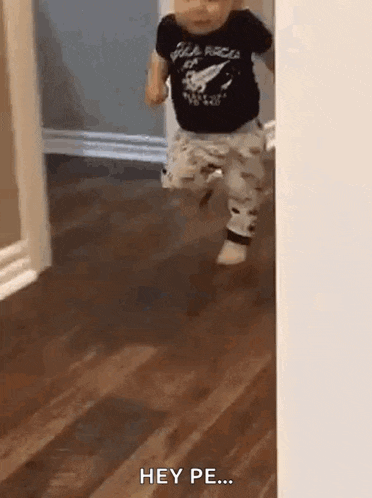 a baby is running through a doorway while wearing a black shirt and pants .