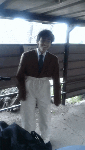 a man in a suit and tie stands in front of a fence with a sign that says 1v2