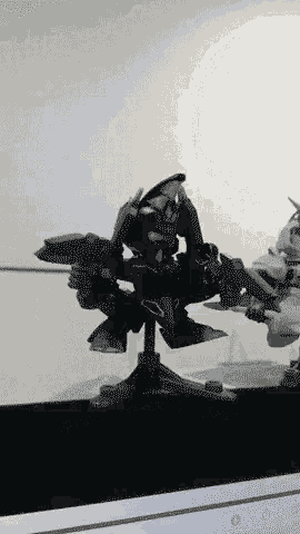 a black and white animated gif of a robot sitting on a table .