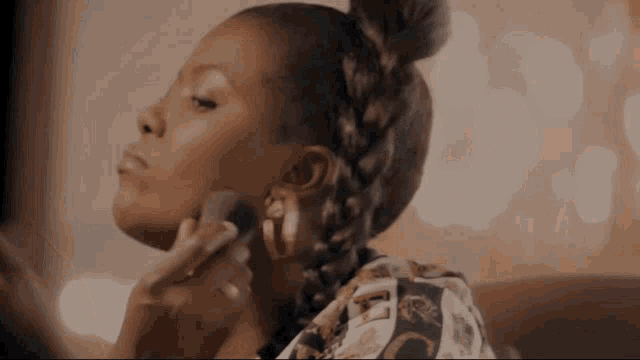 a woman is applying makeup to her face while wearing a shirt with the letter l on it