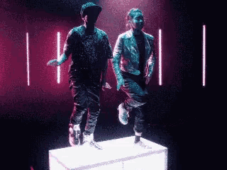 two men are dancing in a dark room with neon lights