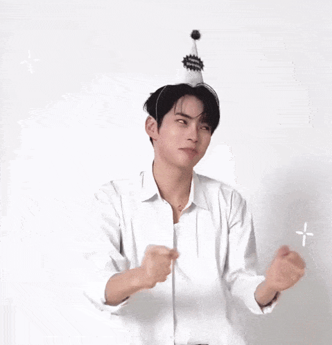 a man in a white shirt is wearing a party hat and making a funny face .