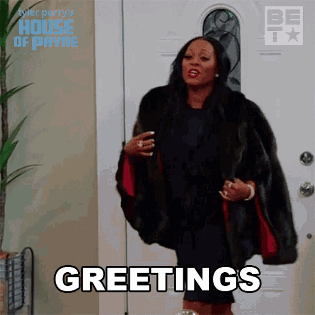 a woman in a fur coat is standing in front of a white door and says greetings