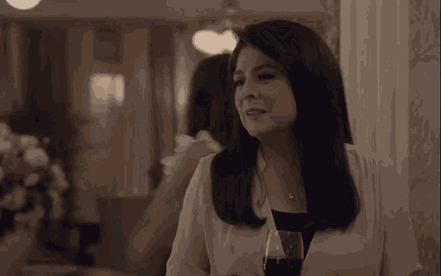 a woman is holding a glass of wine in a living room