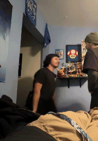 a man in a black shirt is standing in a room with a mushroom on a shelf