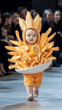 a baby dressed in a bunny costume holding a bowl of french fries