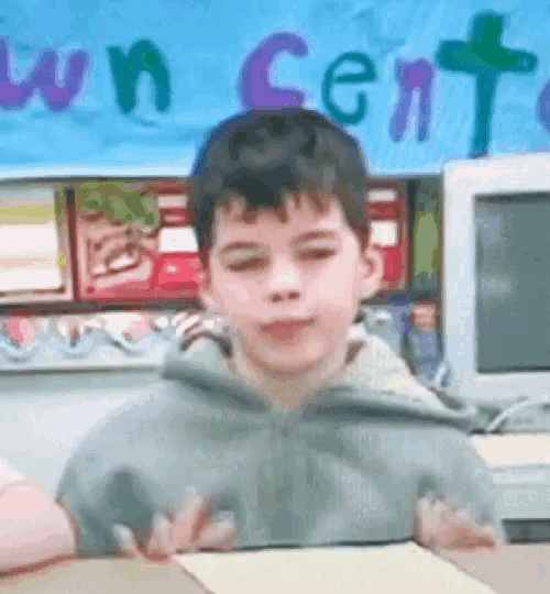 a young boy is sitting at a desk in front of a sign that says ' town center '