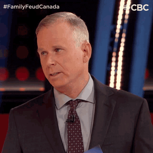 a man in a suit and tie is standing in front of a cbs logo
