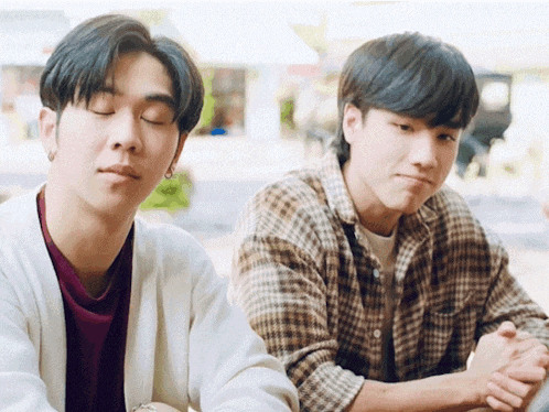 two men are sitting next to each other with their eyes closed