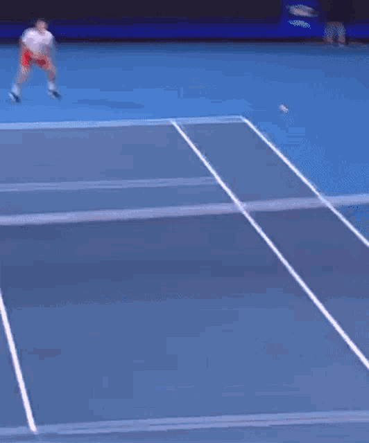 a man in red shorts is swinging a tennis racket at a ball