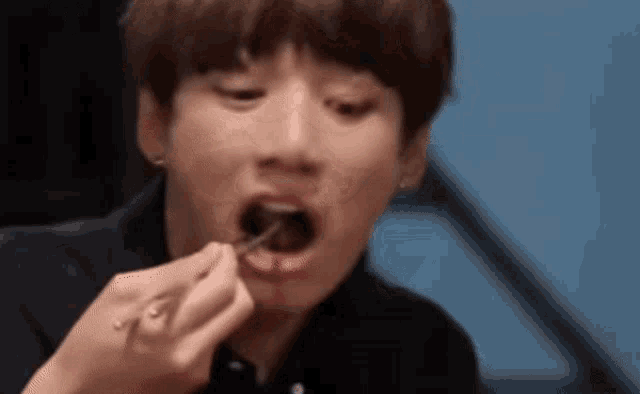 a young man is eating something with a fork and spoon .