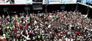 a large crowd of people gathered in front of a sign that says democracy