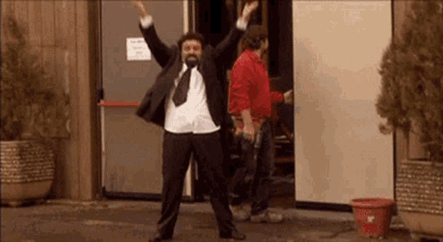 a man in a suit and tie is standing in front of a door with his arms in the air .