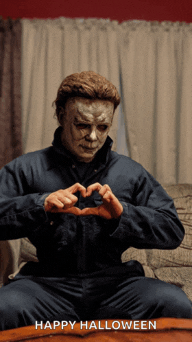 a man in a mask is making a heart shape with his hands and the words happy halloween are below him