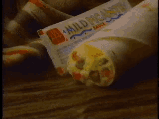 a burrito next to a mild picante sauce