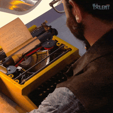 a man is typing on a yellow typewriter with the word talent on the bottom