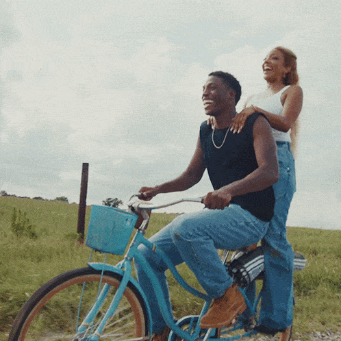 a man and a woman are riding a blue bicycle